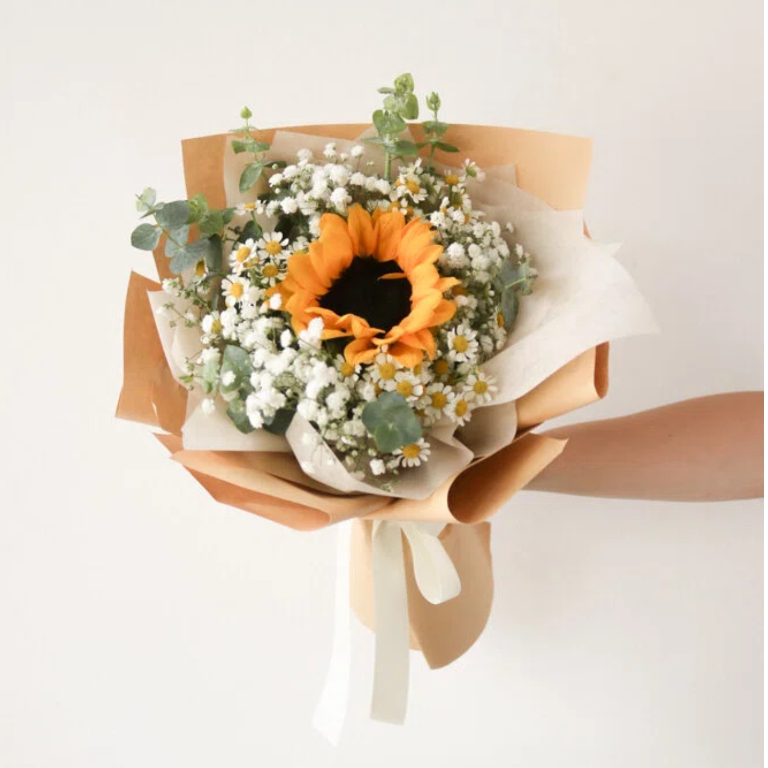 Orange sunflower, white daisies, white baby’s breath in a brown wrap, tied with cream ribbon. Orange sunflower, white daisies, white baby’s breath in a brown wrap, tied with cream ribbon.