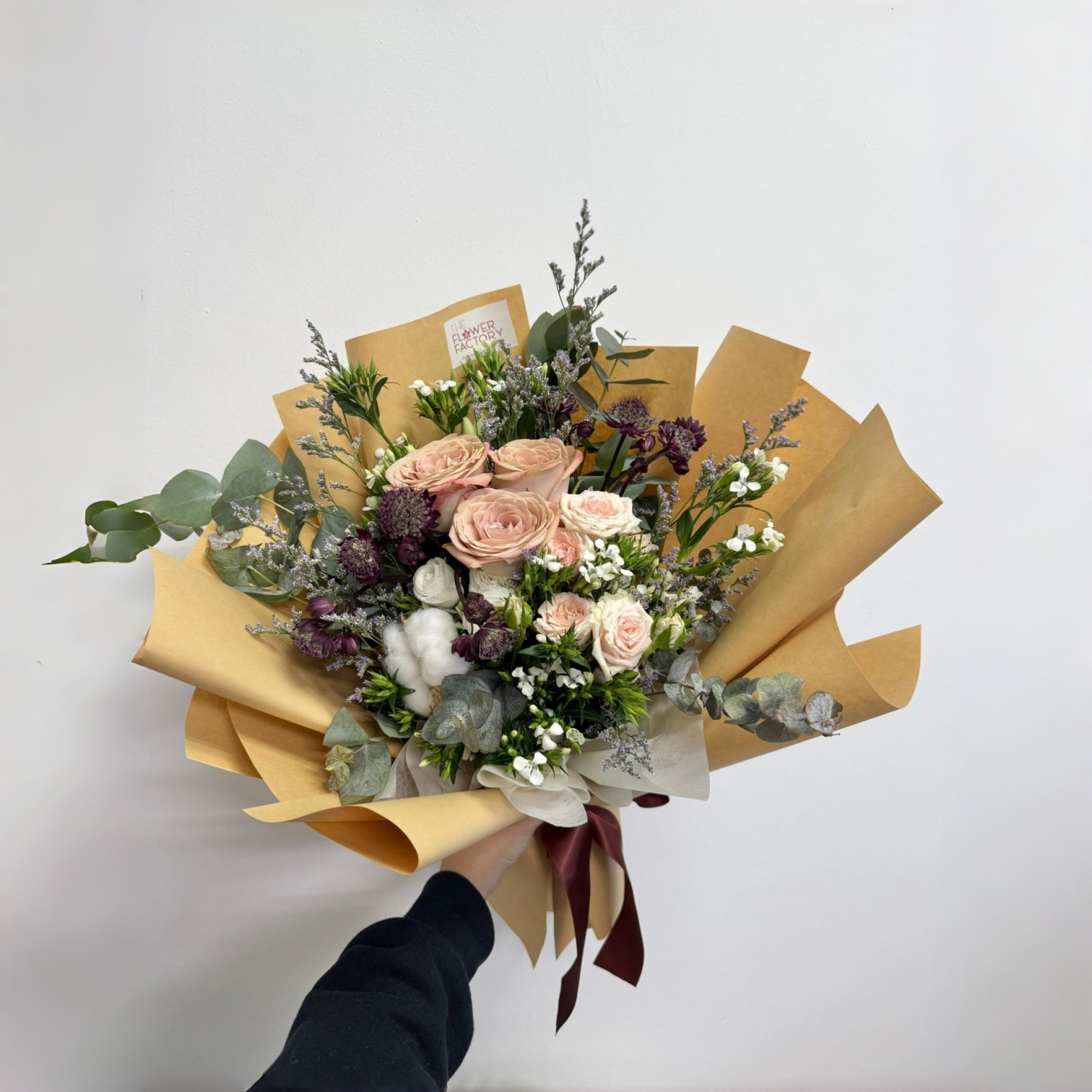 Peach roses and white cotton flowers in brown wrap newspaper red rib Peach roses and white cotton flowers in brown wrap newspaper red rib