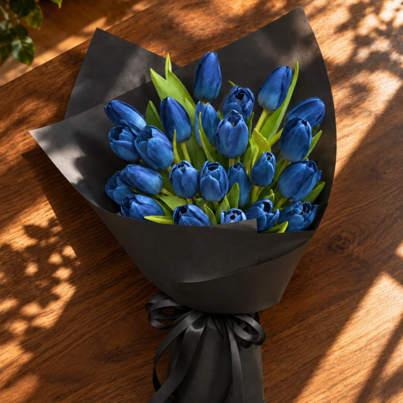24 blue tulips in black wrapping with a matching black ribbon, on a wooden table
